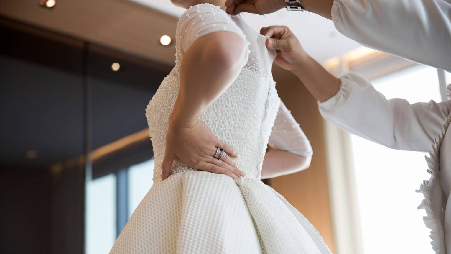 Person zips up bride's white wedding dress 