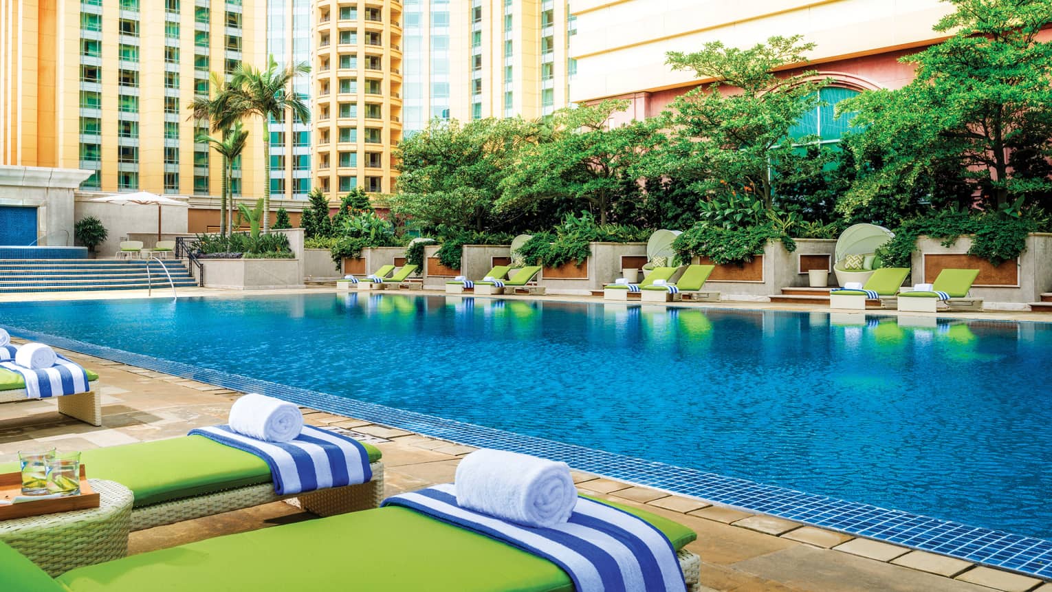 A poolside cabana and lounge chairs nestled between lush trees and a sparkling pool