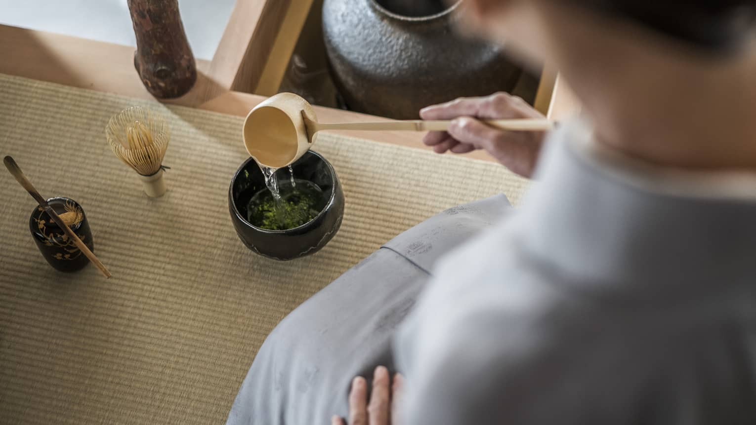 Woman kneels and pours tea from ladle during Tea Ceremony
