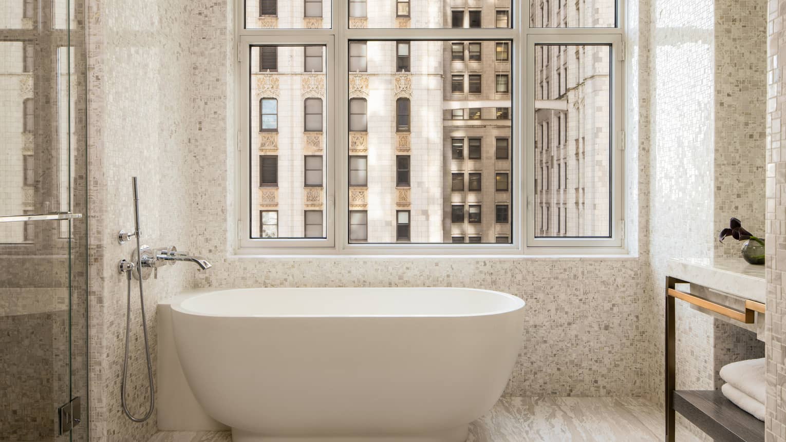 Standalone tub next to a window in a luxury hotel suite bathroom