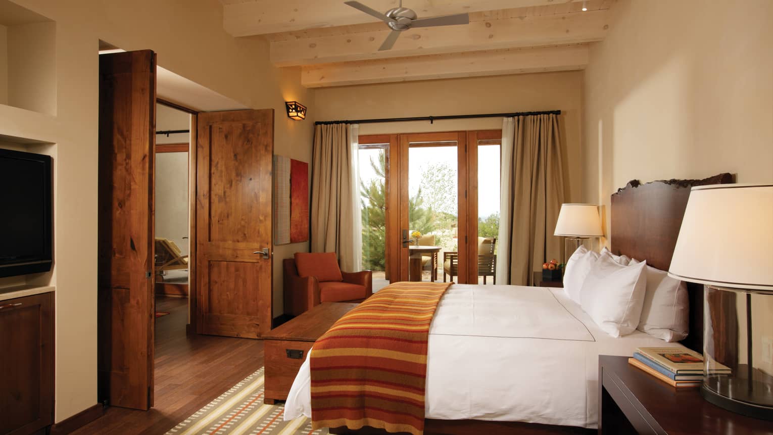 Hotel bed, striped blanket by tall wood doors, window