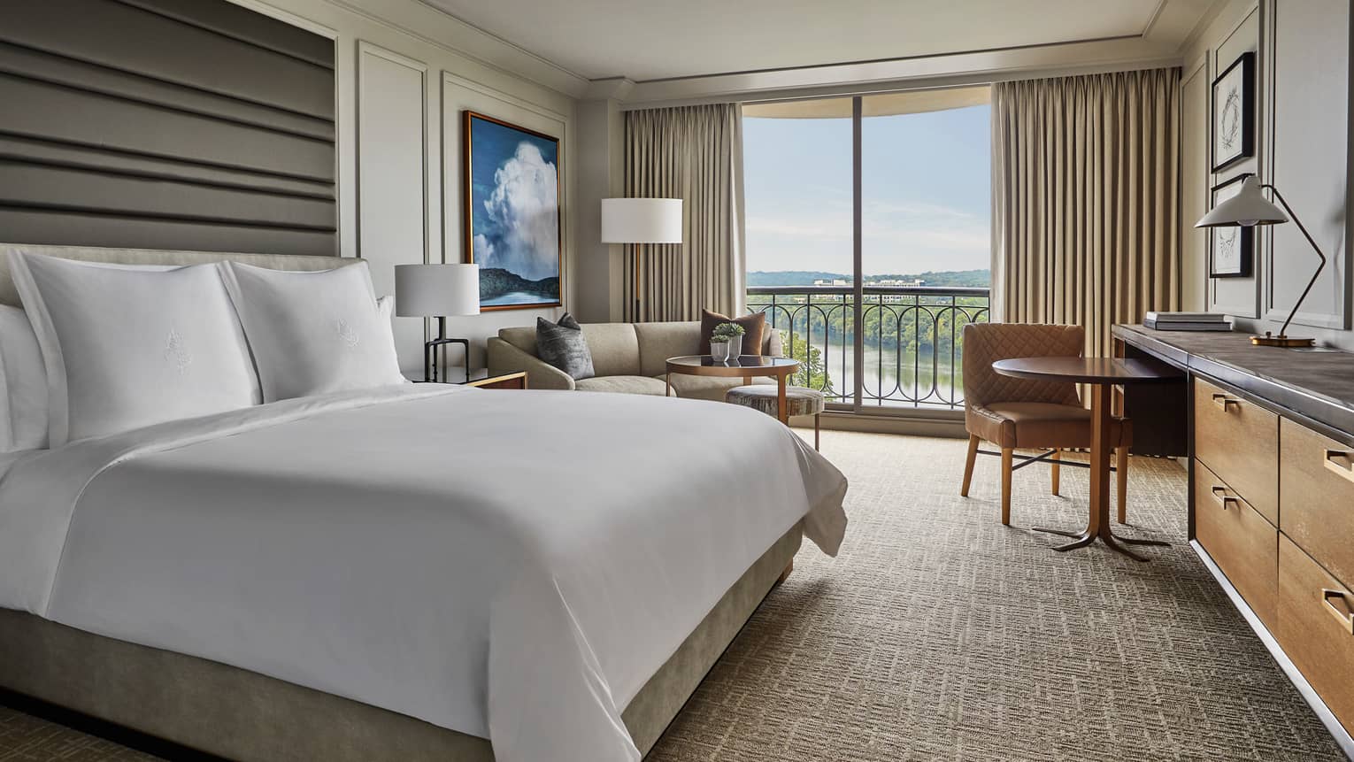 Lake View Balcony room bed, tall padded headboard, sofa, dining table by window