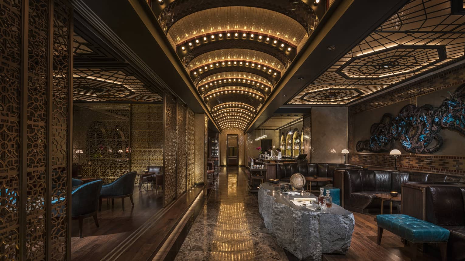 Dimly lit Charles H Bar lounge with stone table, leather banquettes, arched lights 