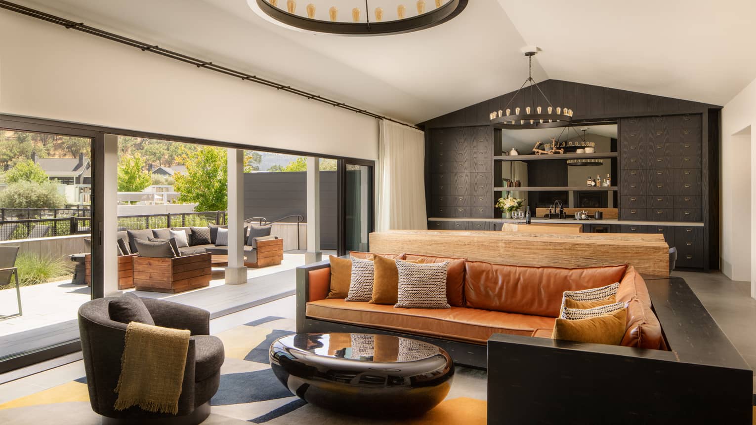Large great room featuring a leather sectional sofa, modern coffee table and chair, and full-length doors that lead to terrace