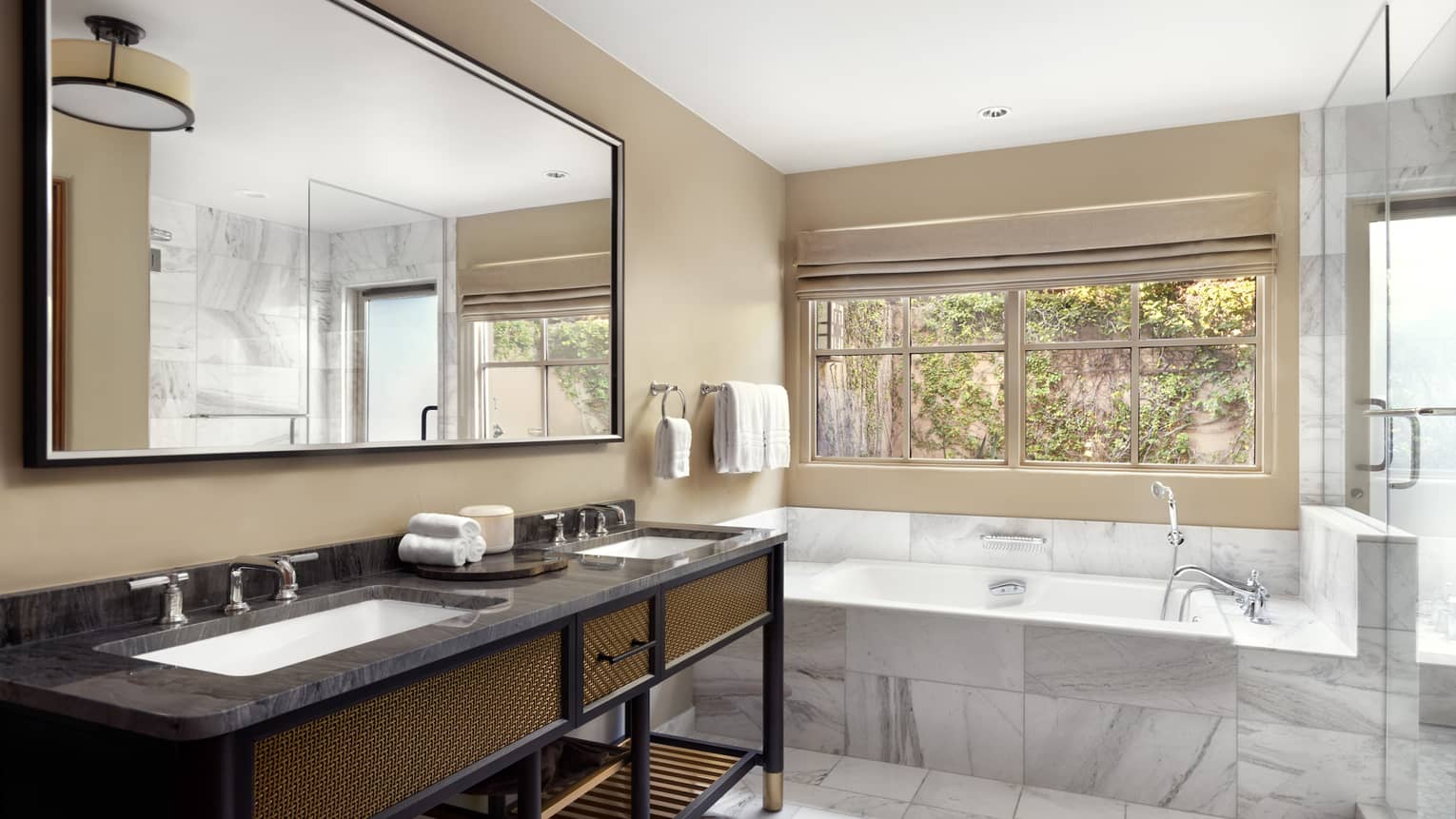 Bathroom with marble floor and tub, separate glass shower, double vanity and a window with tree view