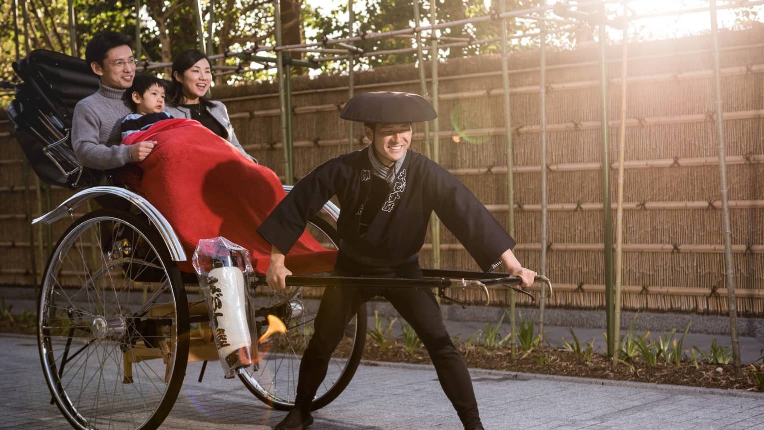 Family enjoying a traditional rickshaw ride with a smiling driver dressed in Japanese attire at Four Seasons