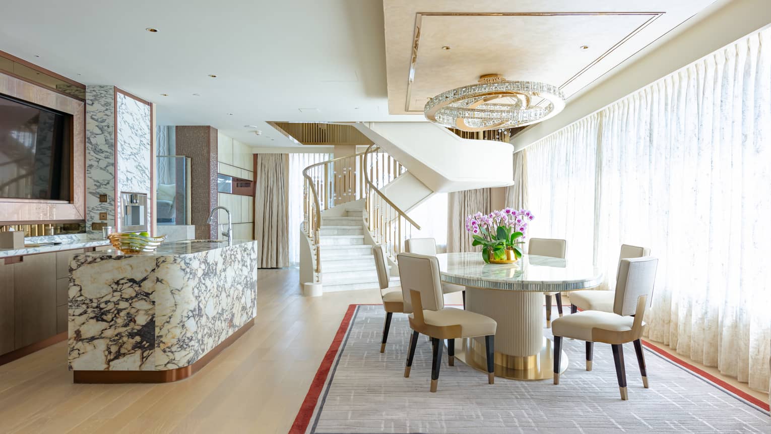 A luxurious, open-plan kitchen and dining area adorned in marble and gold-trimmed finishes. 