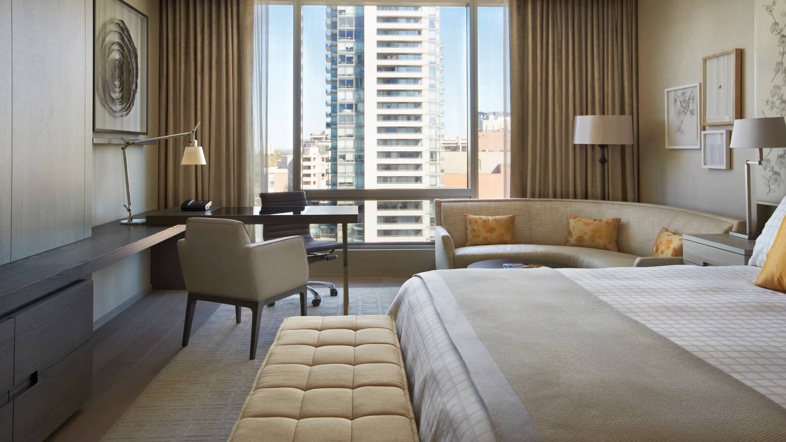 Yorkville Premier Room bed with plush bench at foot, curved sofa, desk and chairs by window