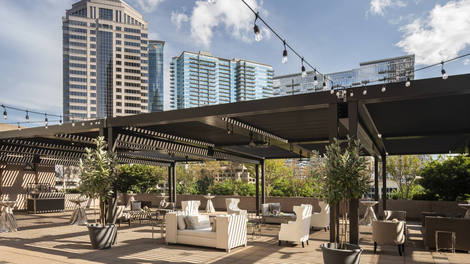 Fifth-floor rooftop terrace during the day with modern white sofas under large wood pergola