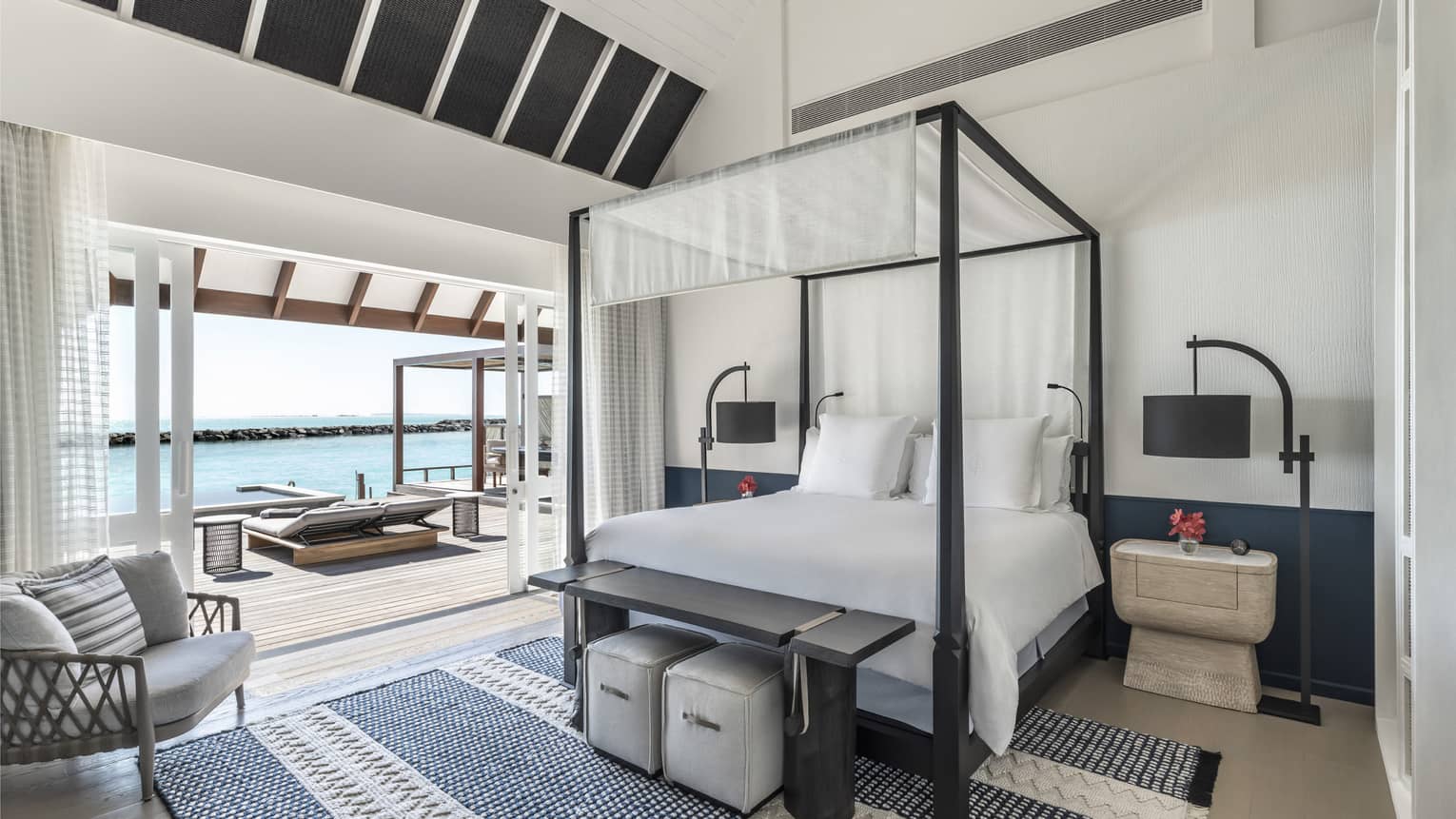 Bedroom with four-poster canopied bed with doorway leading to pool deck with cabana