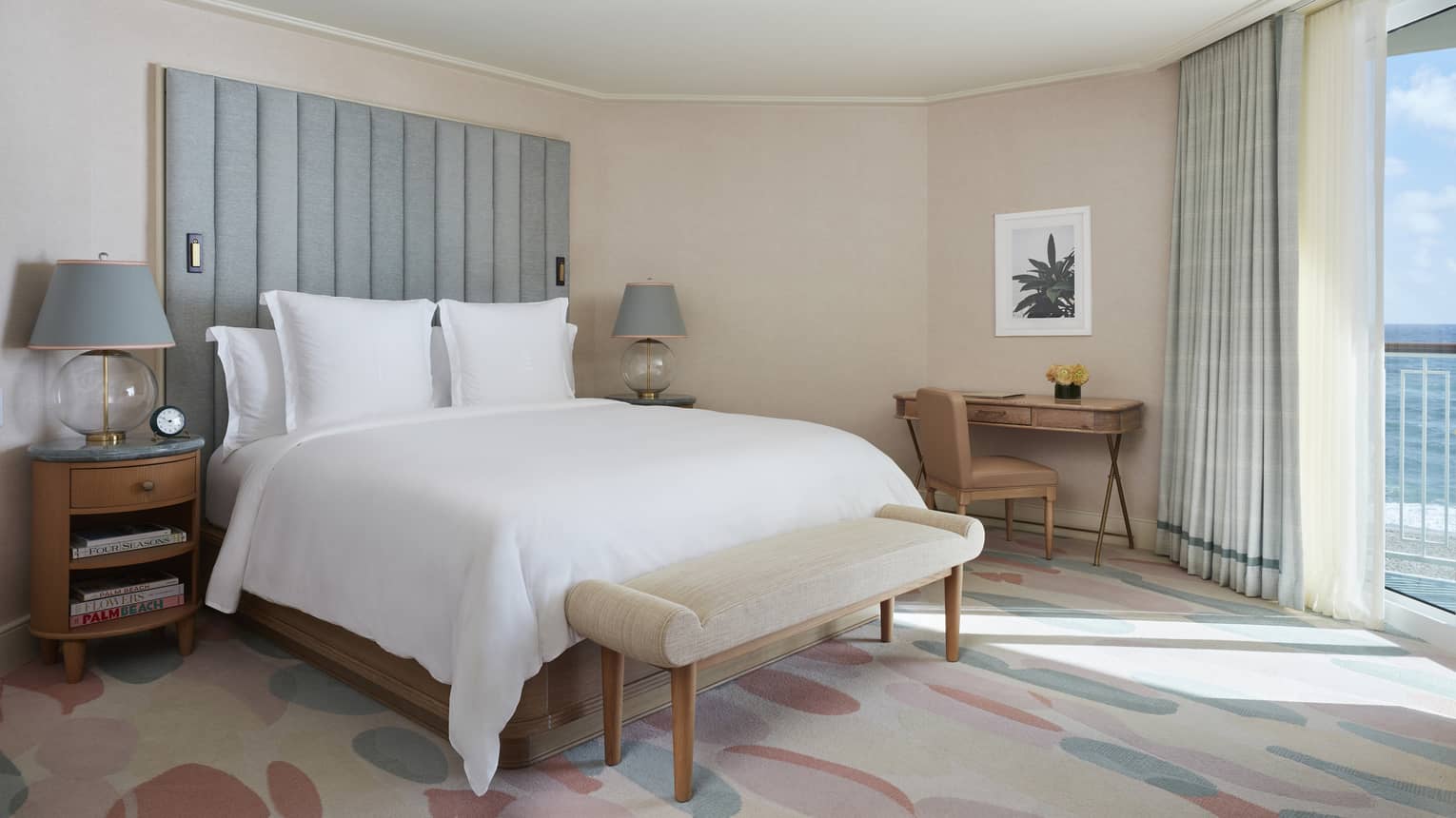 Bedroom of a hotel suite, with floor-to-ceiling views of the ocean