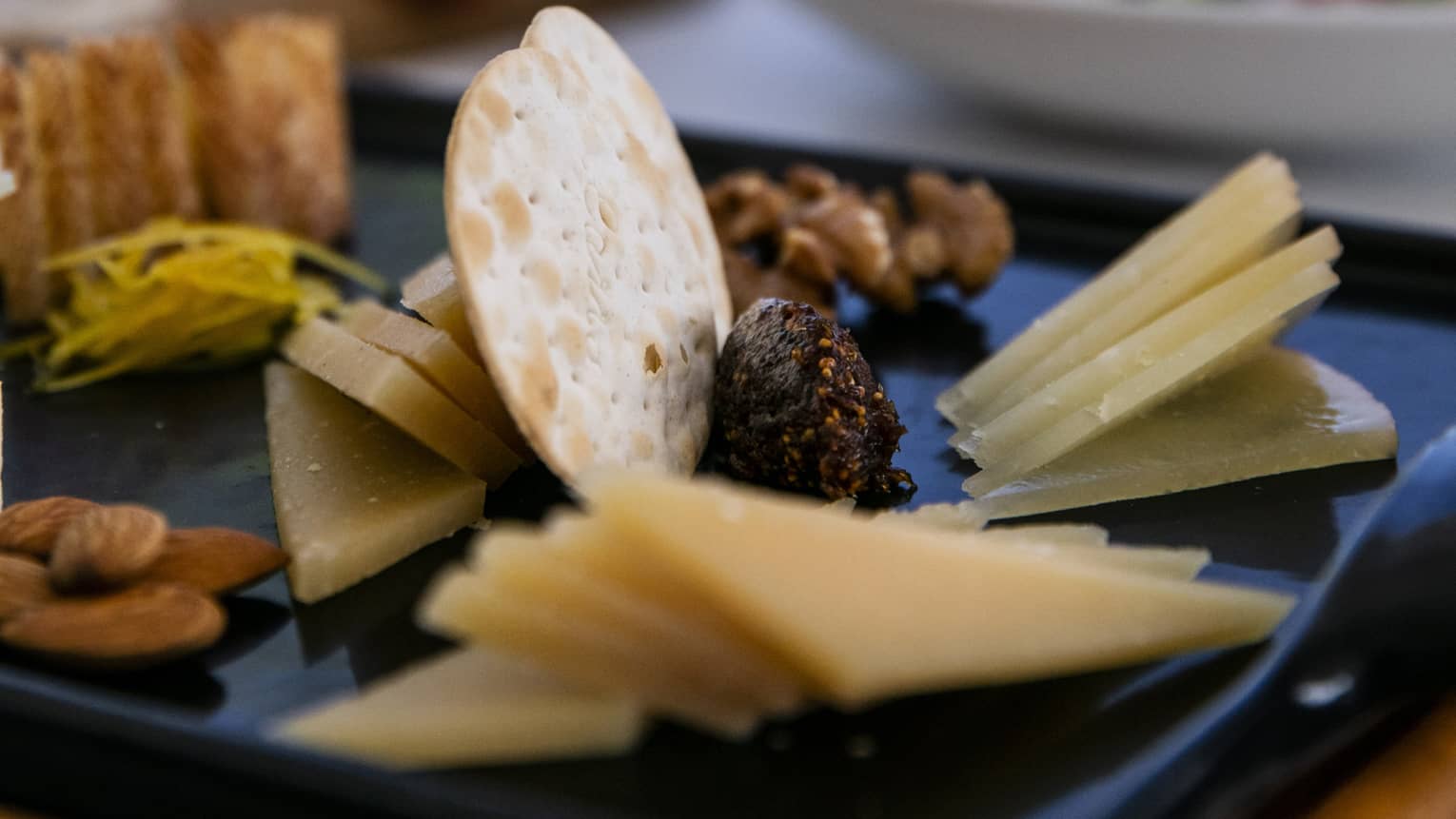 A charteurtie board with cheese, crackers, almonds and raisins