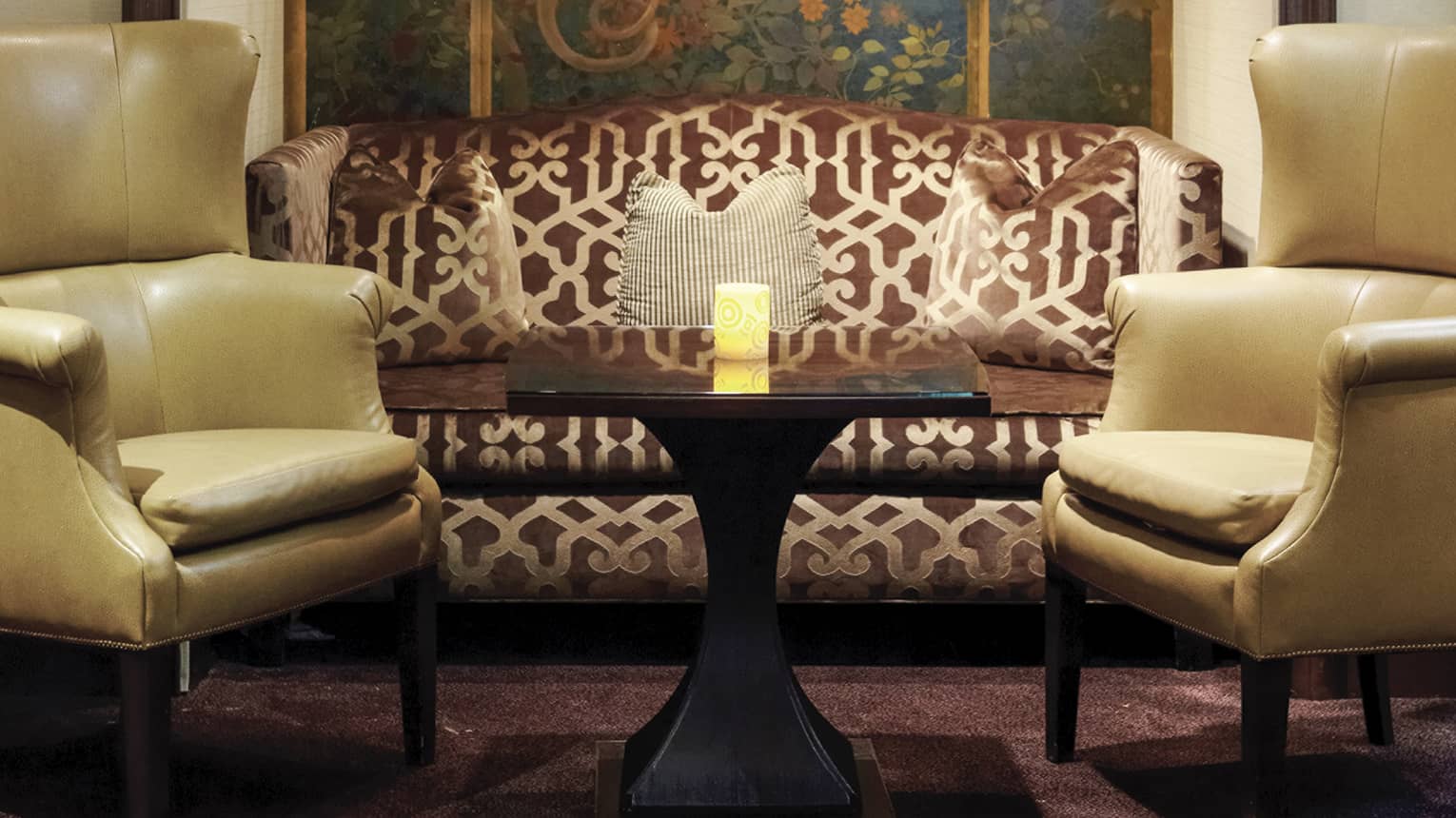 Windows Lounge brown silk patterned sofa, yellow armchairs under mural, glowing candle on table