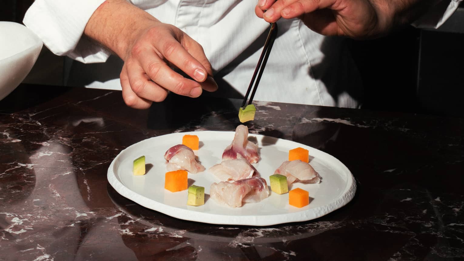 A chef adds garnishes to a plate of food
