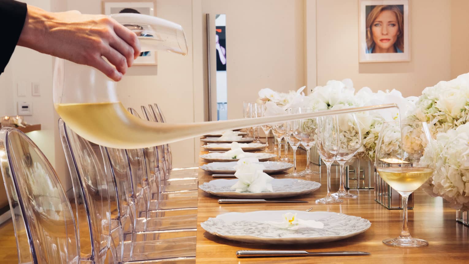 Wine being poured into glasses on a long wooden table.