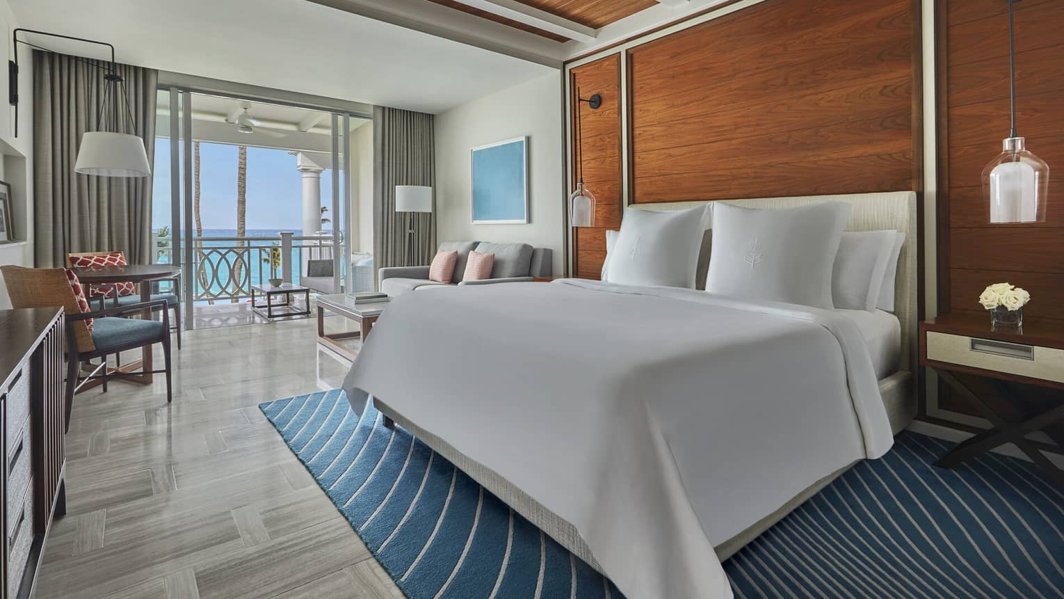 Luxury ocean-view bedroom with a large bed, seating area and private balcony