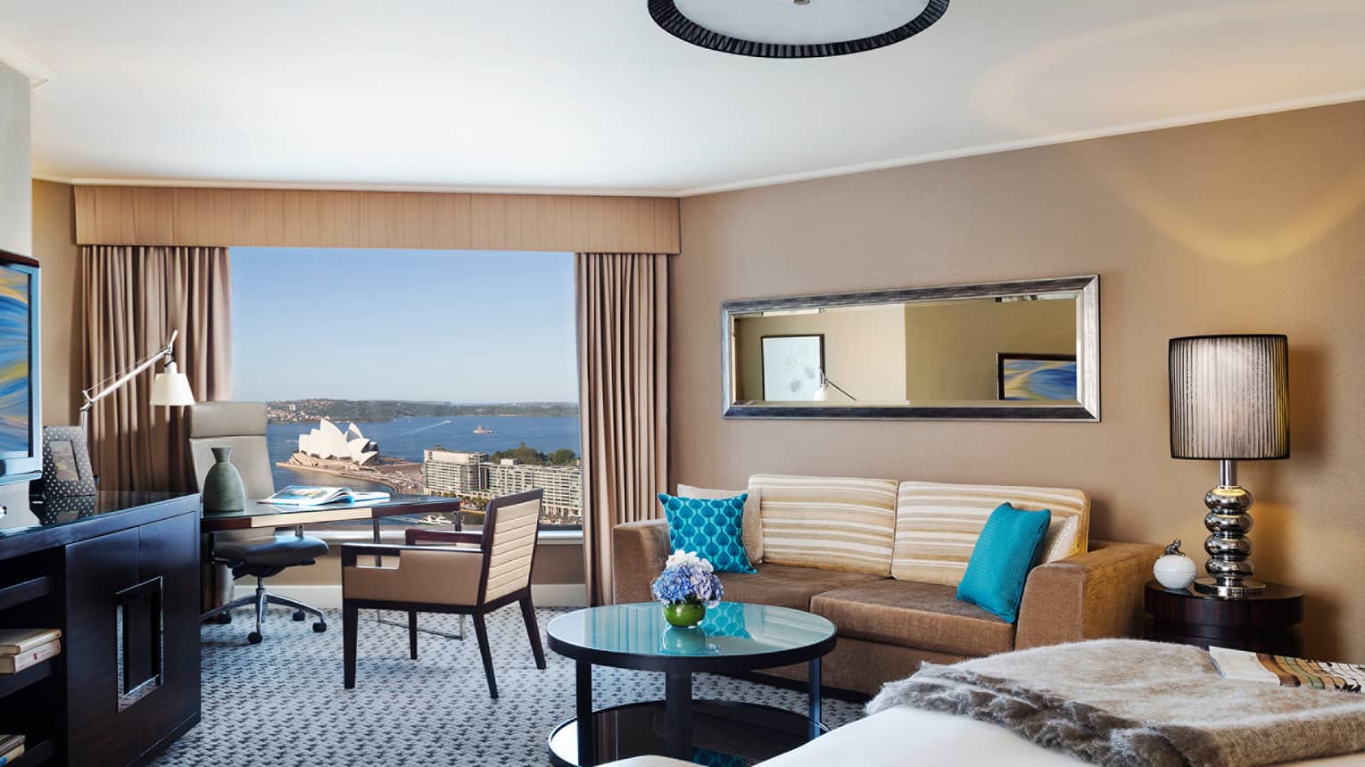 Premier Full Harbour Room, edge of bed, table with flowers, velvet sofa and blue pillows