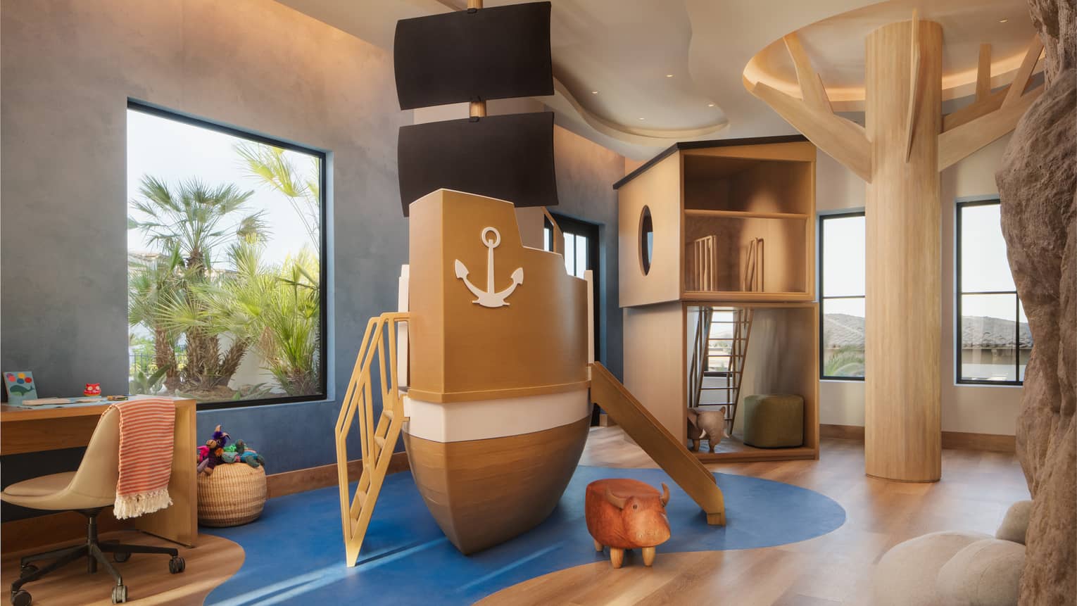 Children's playroom with a large-scale pirate ship play set, wooden tree, desk and climbing fort