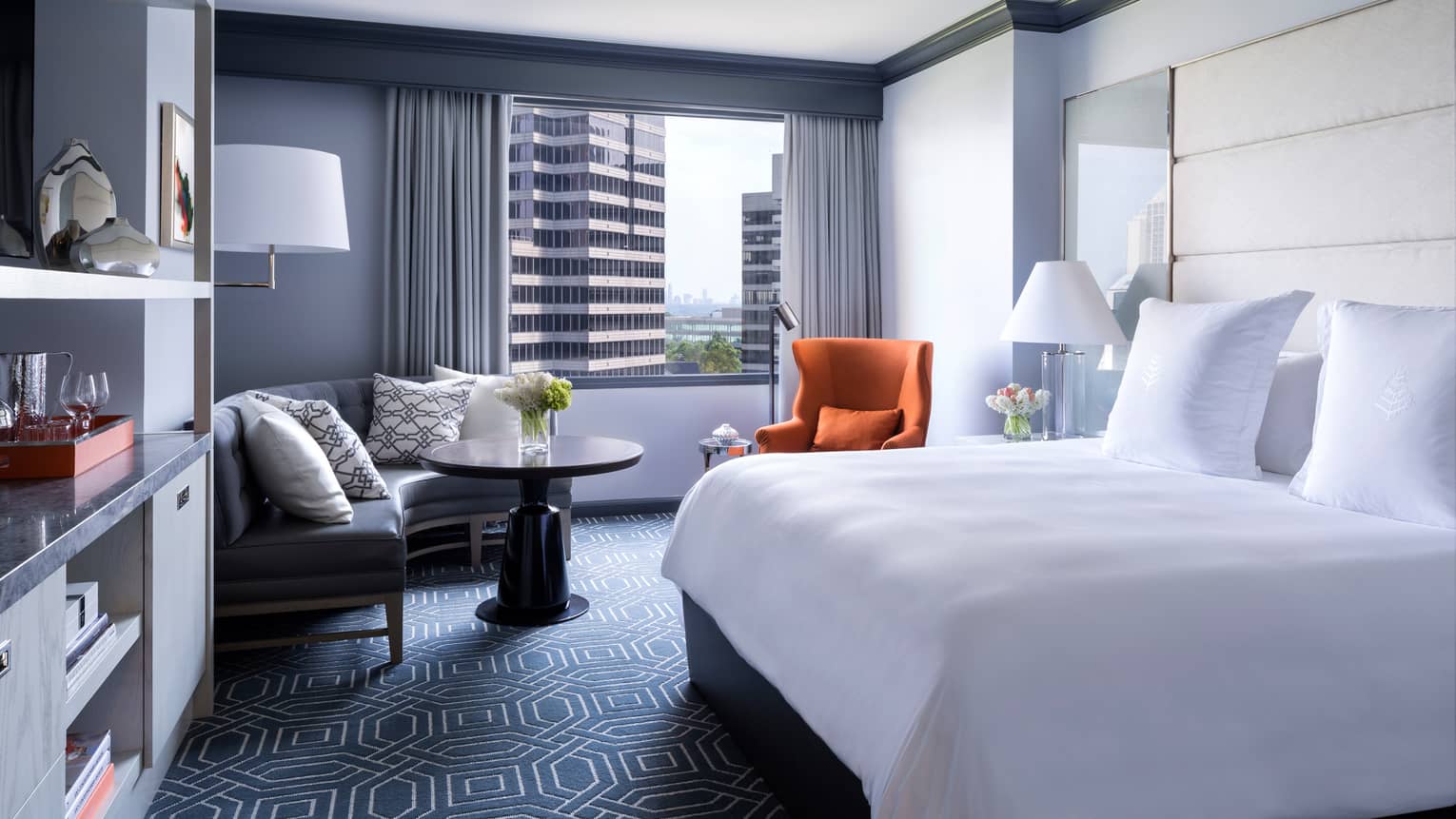 Midtown Deluxe Room bed, blue carpet, marble bar, curved corner sofa, orange accent chair