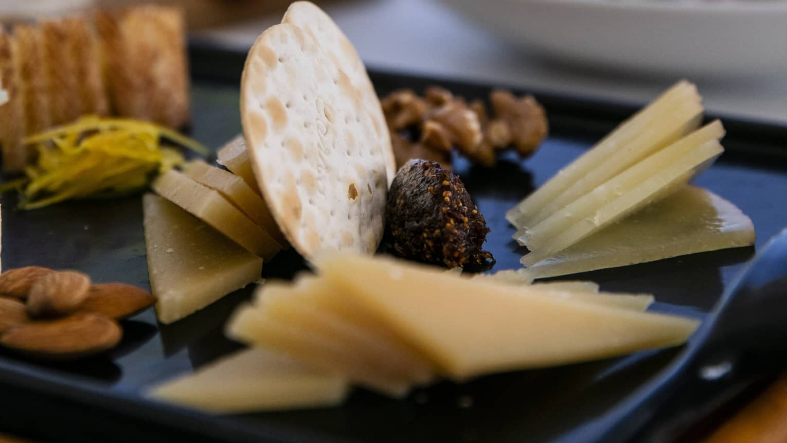 A charteurtie board with cheese, crackers, almonds and raisins