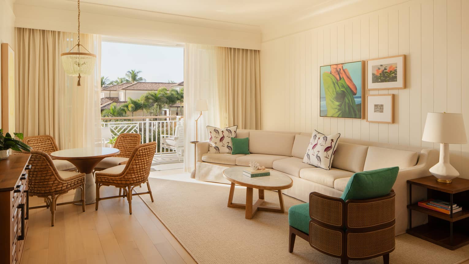 Luxury resort suite living room featuring a sofa, arm chair, round dining table with four chairs, and balcony