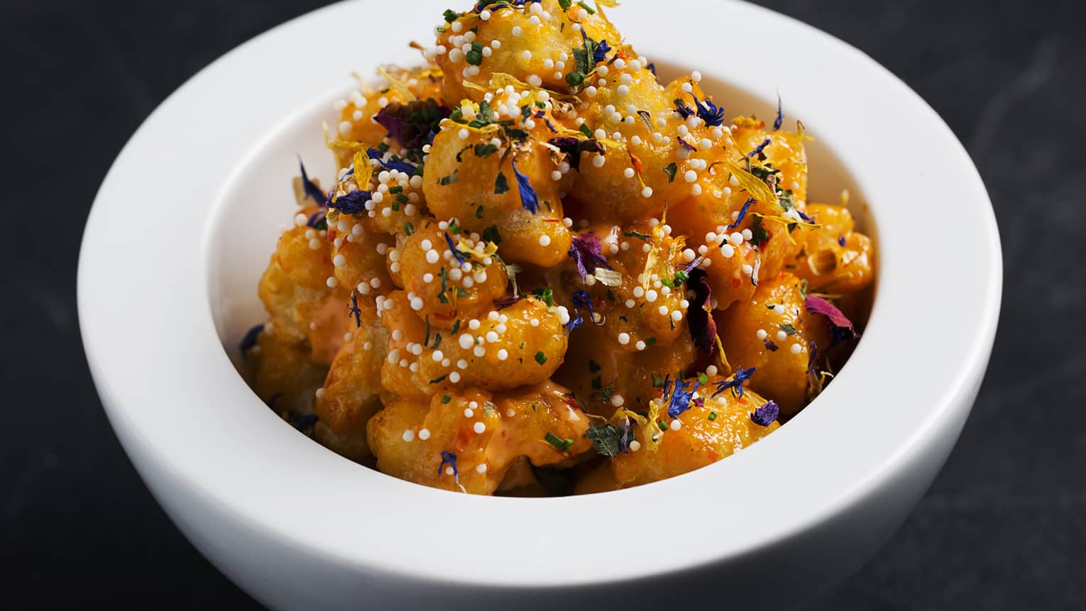 Popcorn shrimp in a red sauce served in a white ceramic bowl.
