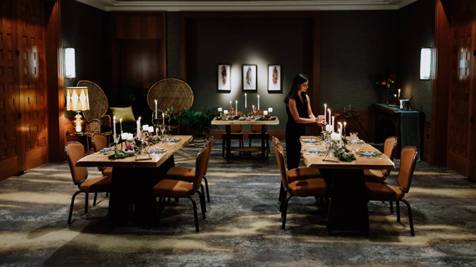 Intimate wedding dinner setup in a luxurious dining room at Four Seasons Whistler. The room features dark wood paneling and soft lighting, creating a warm and inviting atmosphere. Two wooden tables are elegantly set with white candles, floral arrangements, and fine dinnerware. A woman in a dark dress adjusts the table settings, preparing for the event. The sophisticated decor and thoughtful arrangement reflect a serene and exclusive wedding venue.,Intimate wedding dinner setup in a luxurious dining room at Four Seasons Whistler. The room features dark wood paneling and soft lighting, creating a warm and inviting atmosphere. Two wooden tables are elegantly set with white candles, floral arrangements, and fine dinnerware. A woman in a dark dress adjusts the table settings, preparing for the event. The sophisticated decor and thoughtful arrangement reflect a serene and exclusive wedding venue.
