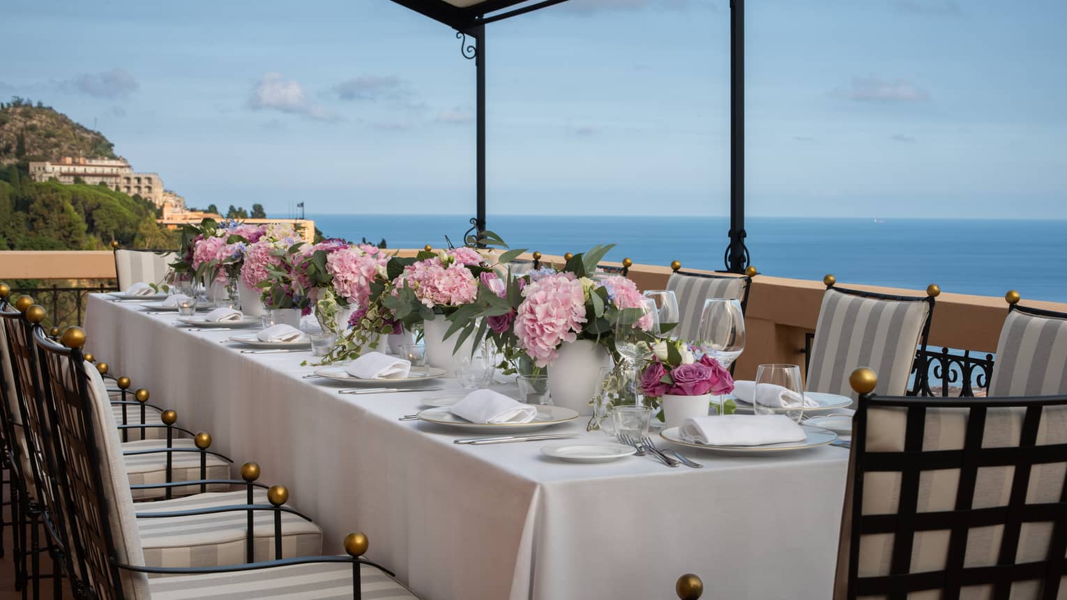 Long dining table on outdoor terrace with sea view