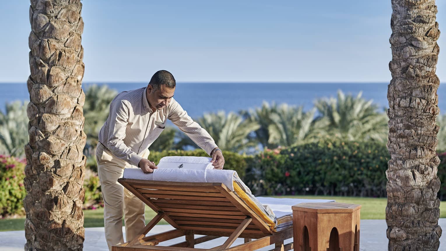 Man arranging a pool chair with sea in background