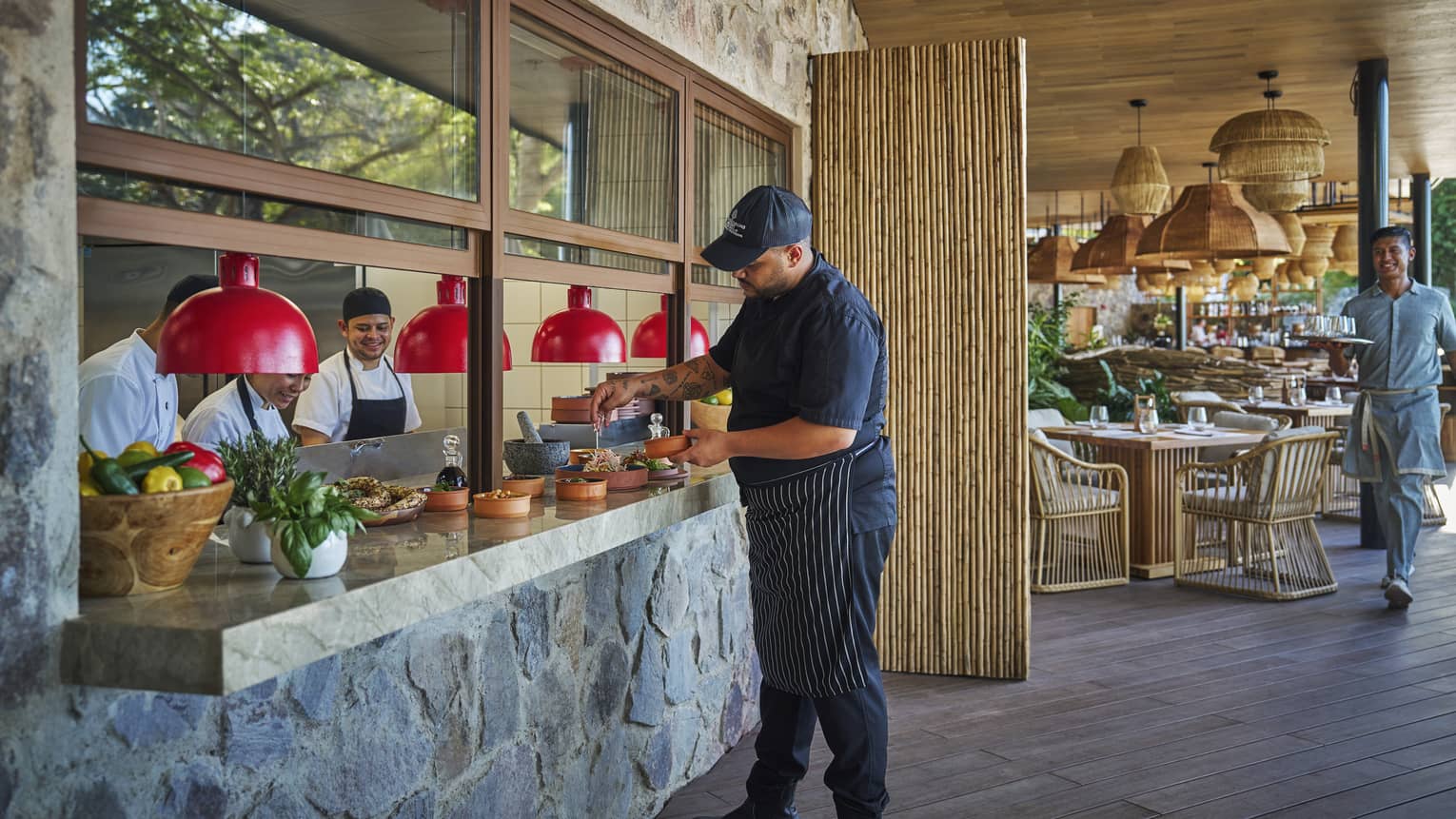 Server wearing black shirt and pants picks up food from a stone counter
