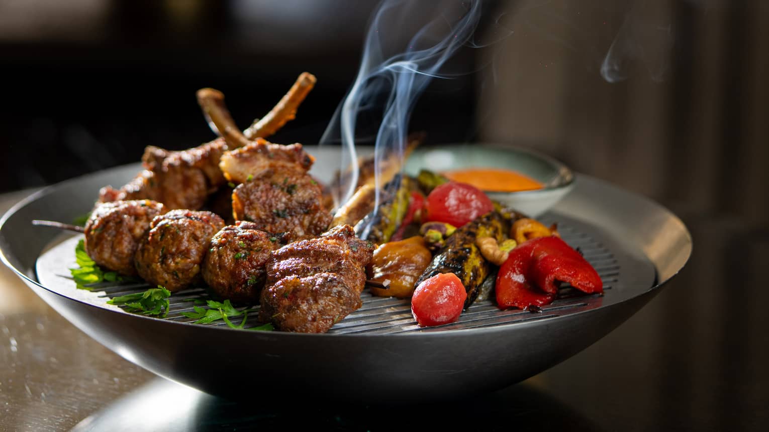 Steaming mixed grilled meat with red pepper on metal plate