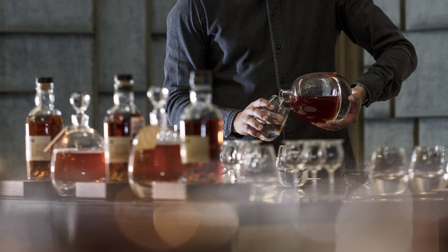 A bartender pours rum from a round bottle into a glass