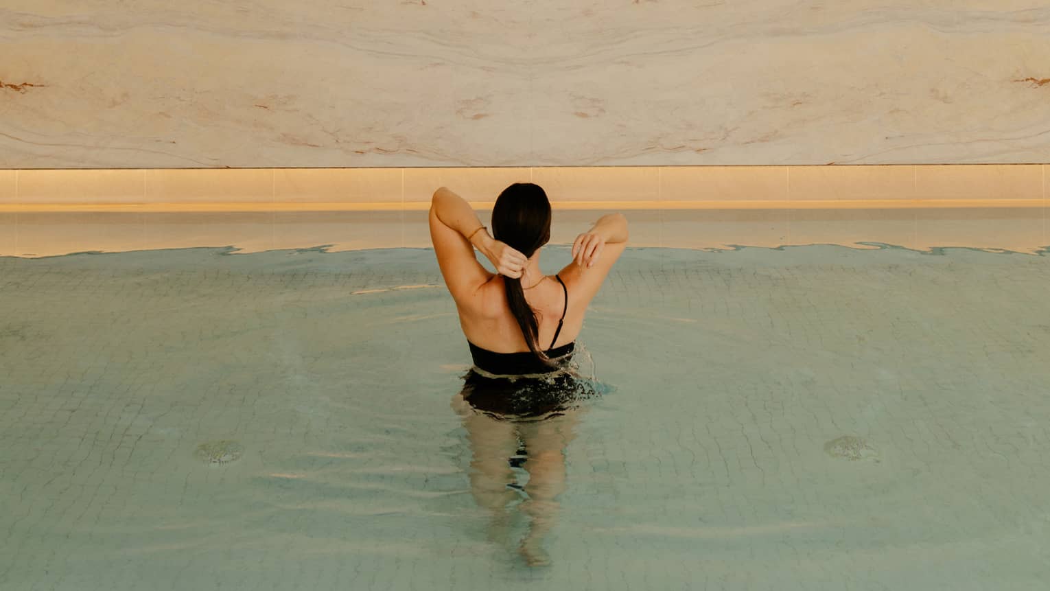 Person wearing a swimsuit and standing in the pool water.