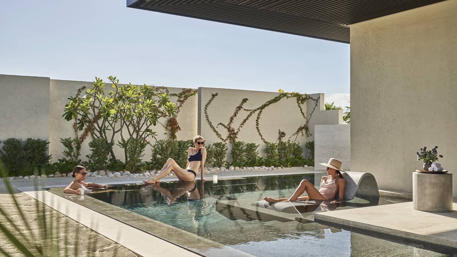 Three women lounging around a small outdoor pool.