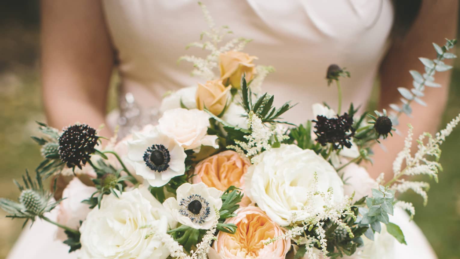 Bride holding floral garden wedding bouquet with white and peach flowers