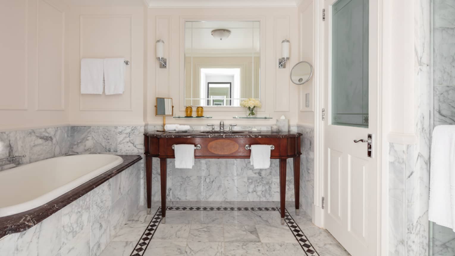 Bathroom with marble accents, large soaking tub, double wooden vanity, mirror