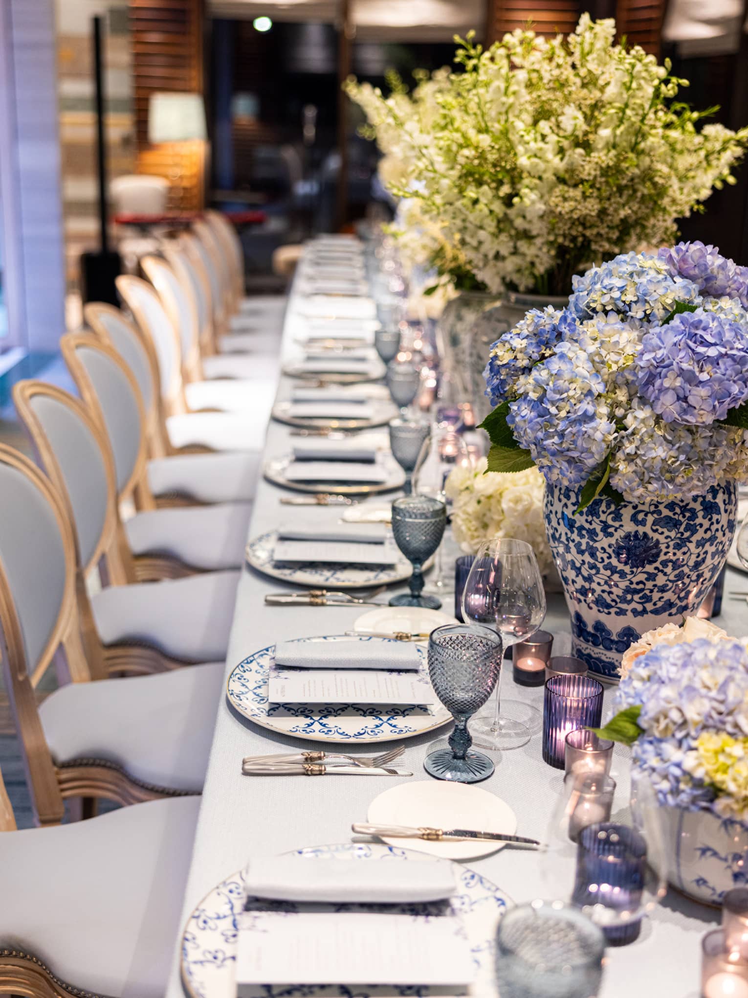 Elegantly set dining table with hydrangea bouquets, flanked by formal dining chairs