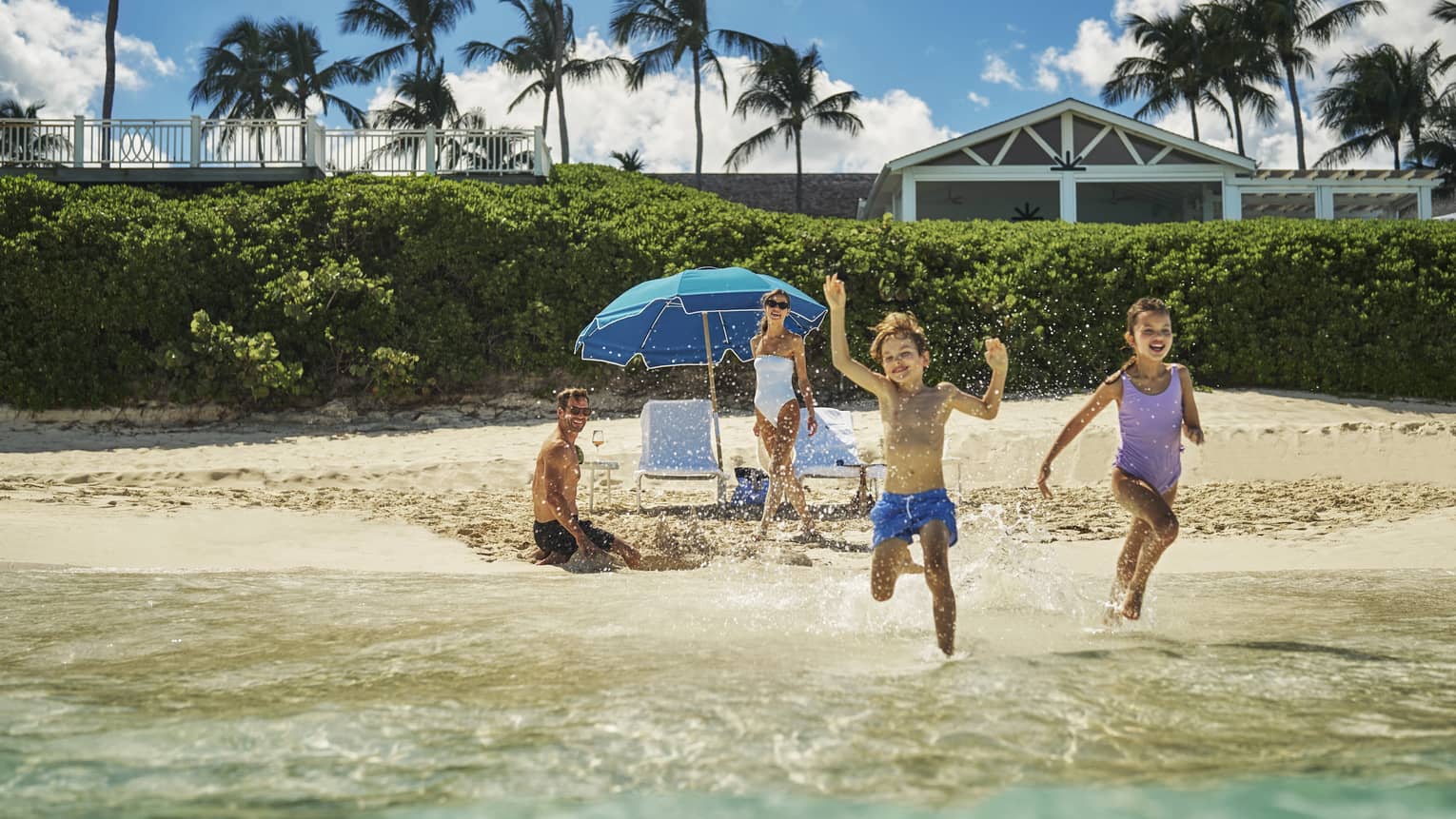 Children playing in the ocean water while parents watch from the sand.