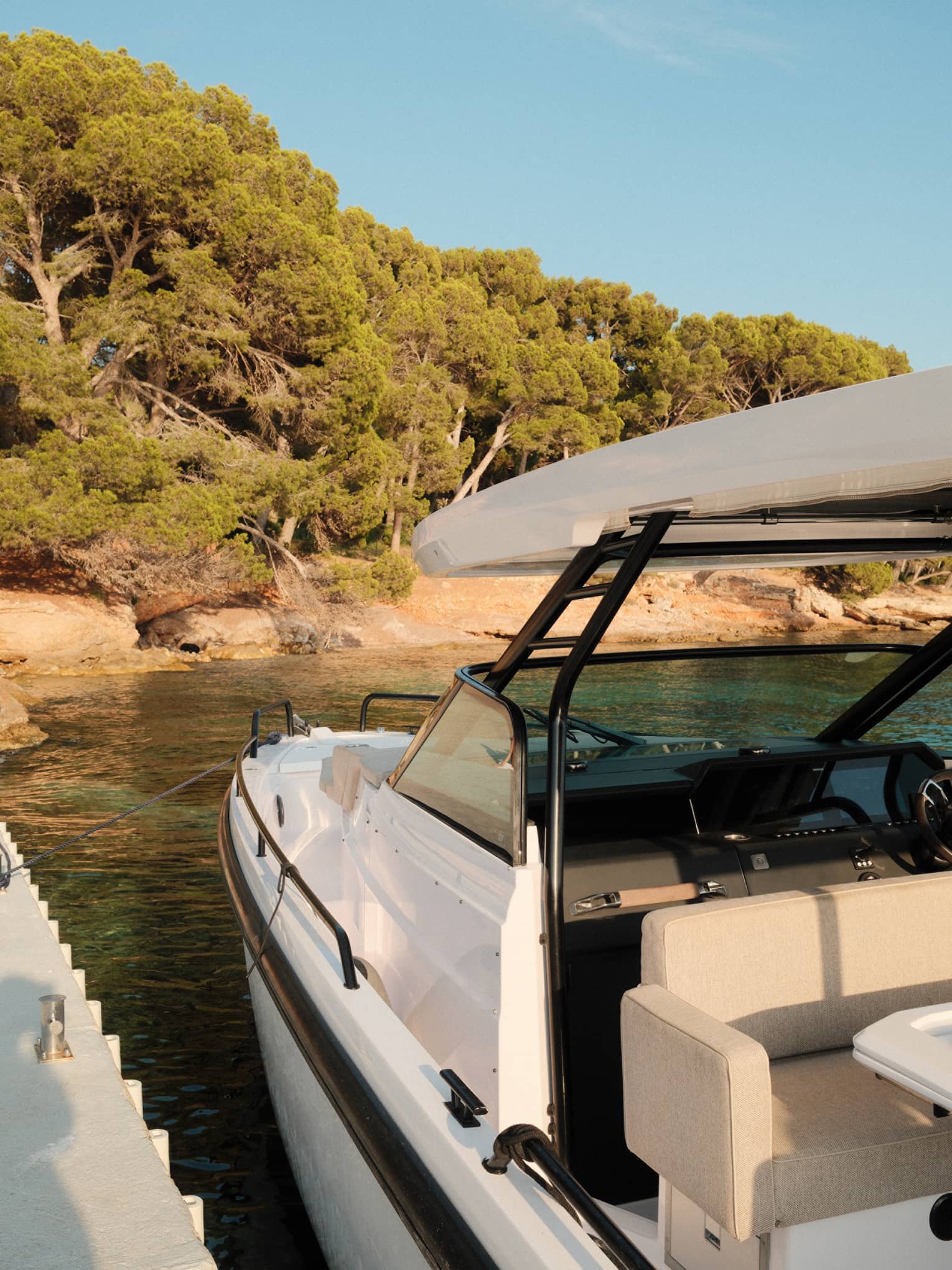 A white boat is docked near a tree-lined island shore