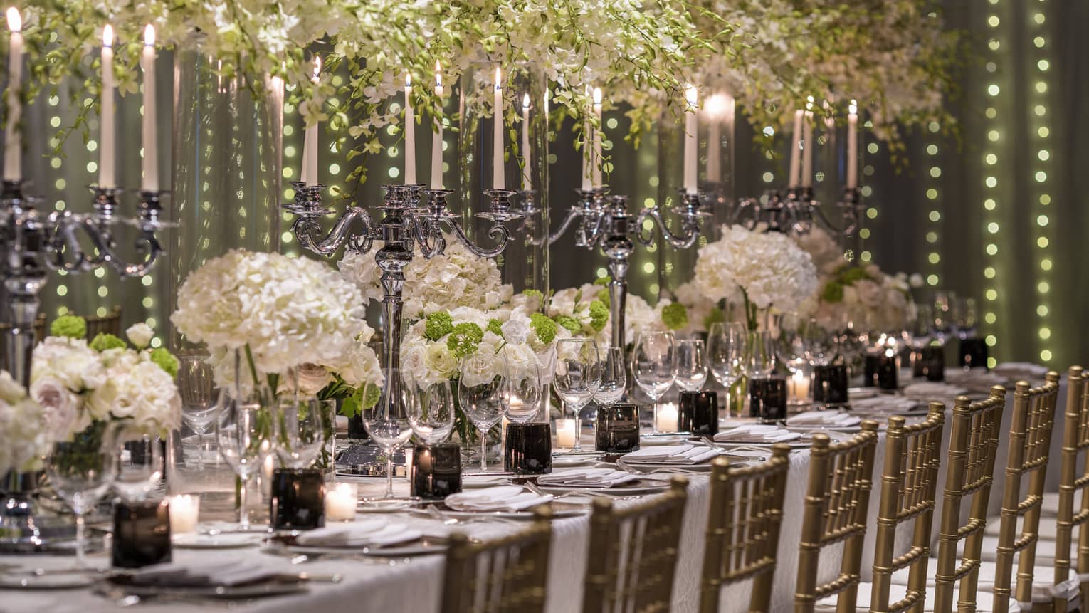 Elaborate white flowers and candelabras serve as the centerpiece of a dining arrangement