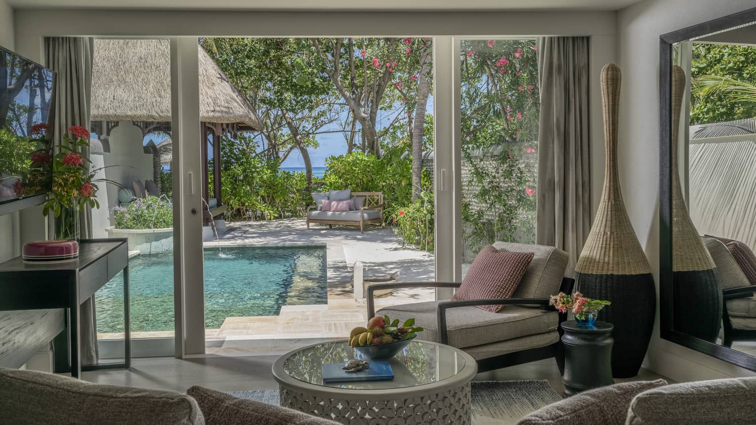 Living room opening to pool deck, with beach in the distance