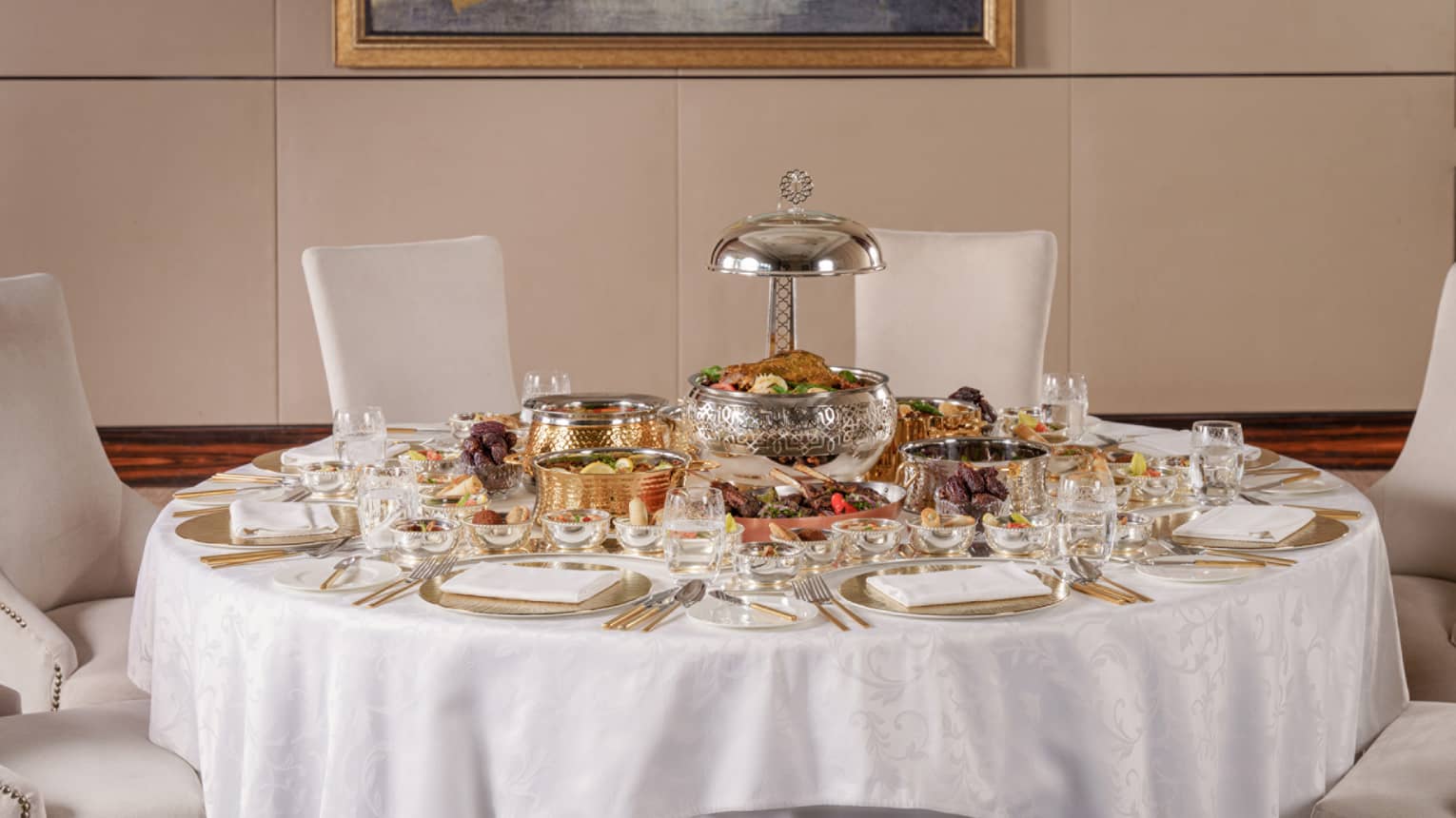A round table covered in white linens is set for a Ramadan feast for six