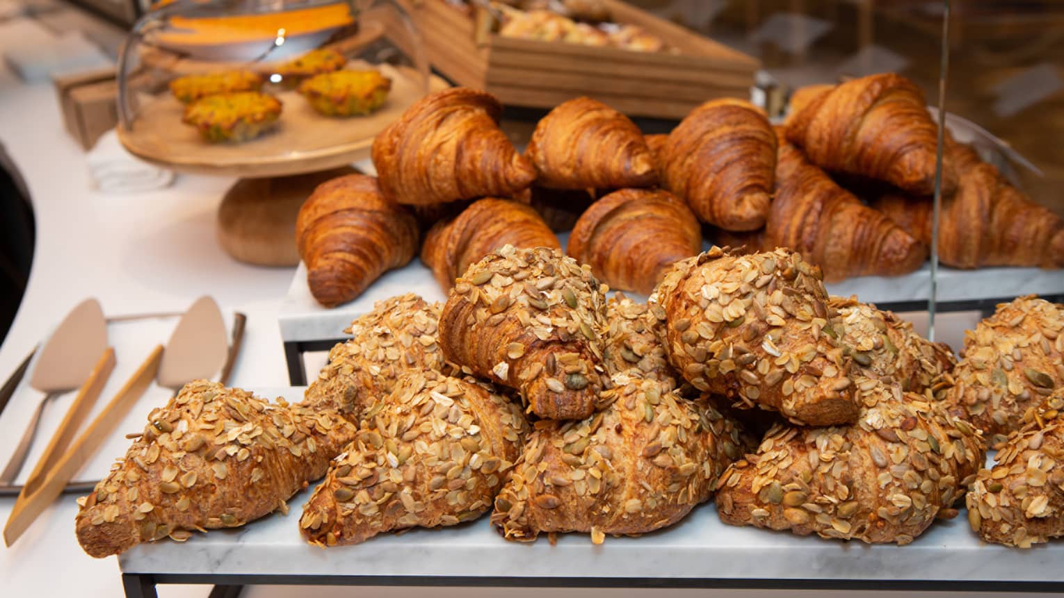An assortments of croissants and bread on trays.