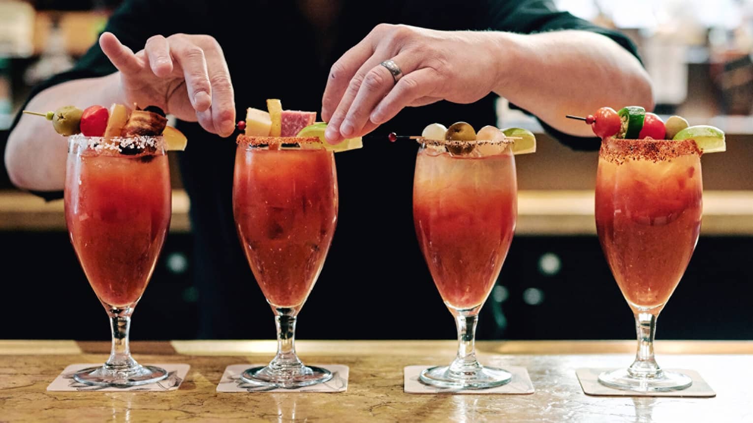 A row of four Bloody Marry’s being garnished.