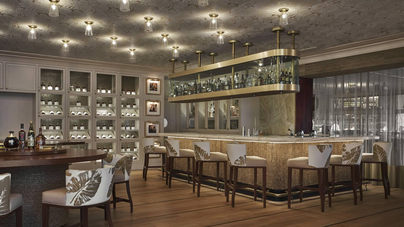 A dimly lit bar area with a large bar and white stools.