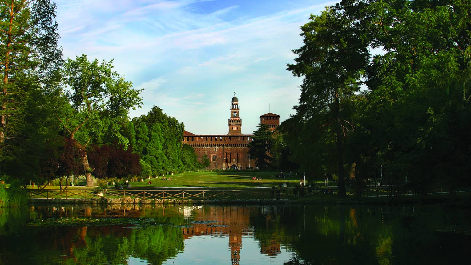 a lake with a reflection of a historic looking building in Castello Sforzesco, Milan