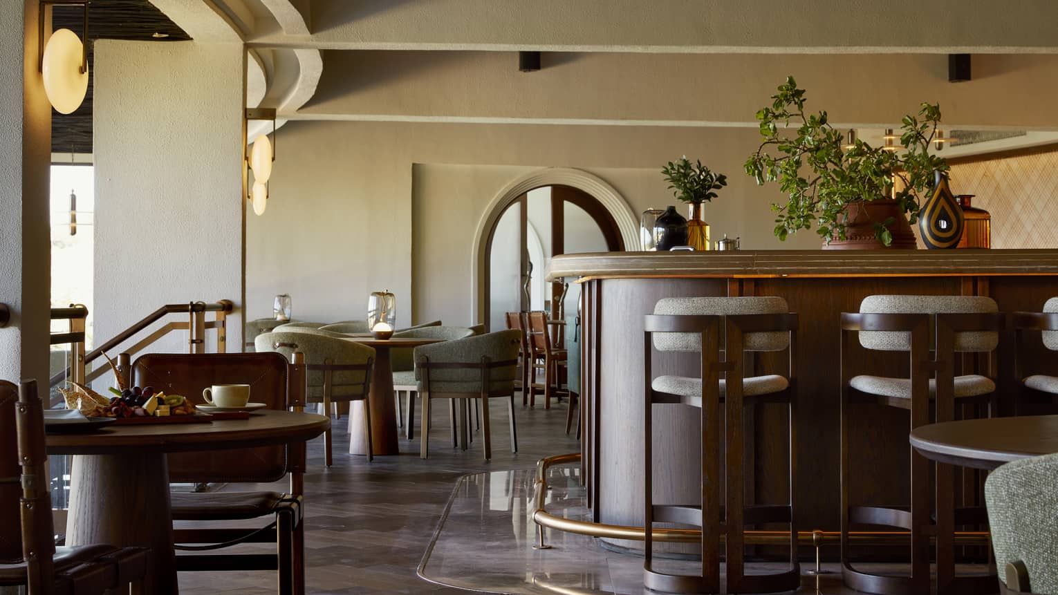 Restaurant with rich dark-brown tables and bar with high ceilings and archways