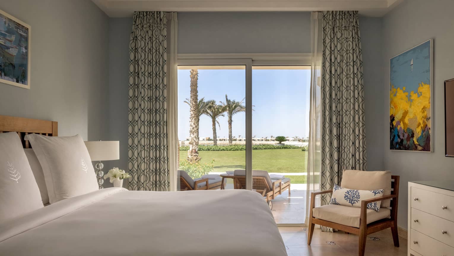 Guest bedroom with king bed, armchair, sliding glass door to terrace