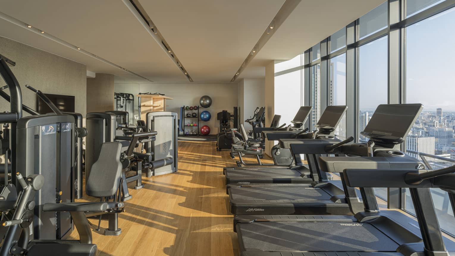 Indoor, light-filled gym at Four Seasons Hotel Suzhou, with a row of treadmills, bikes and other weight training machines
