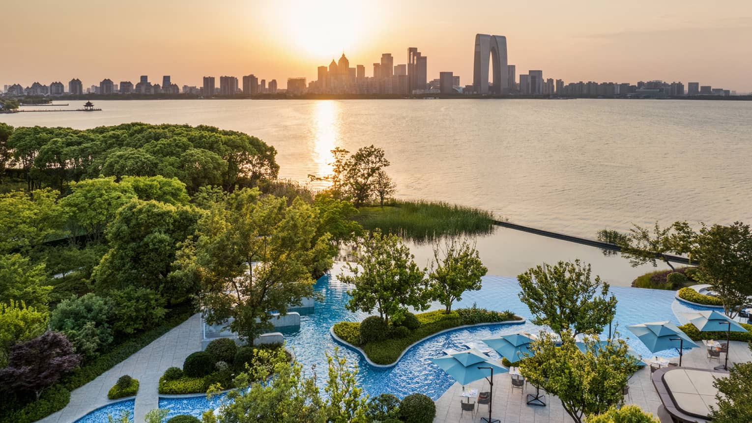 Exterior aerial shot of Four Seasons Hotel Suzhou pool grounds, with Jinji Lake and city centre in the distance